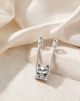 The Little Swing Cat Charm story image on ivory silk and pale stone