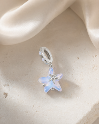 The Opal Starfish Charm story image on ivory silk and pale stone