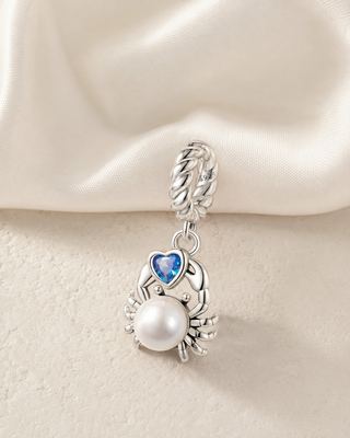 The Pearl Crab Charm story image on ivory silk and pale stone