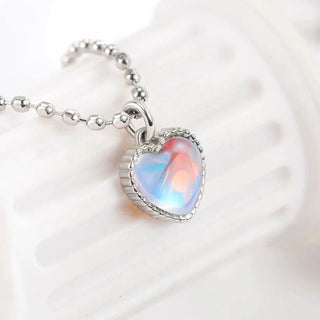 Heart-shaped opal pendant on a silver chain against a white background