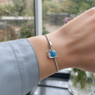 The Slow Magic Snail Charm worn at true scale on a silver charm bracelet