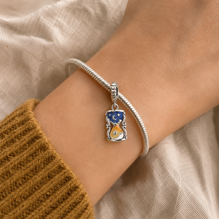 The Between Worlds Hourglass Charm worn on a silver charm bracelet