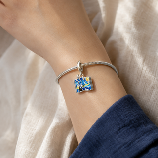 The Painted Night Storybook Charm worn on a silver charm bracelet