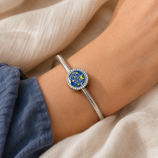 The Starry Canvas Charm worn on a silver charm bracelet